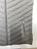 Gray quilted jacket with a close detail of fabric, stitching and zippers on a white background