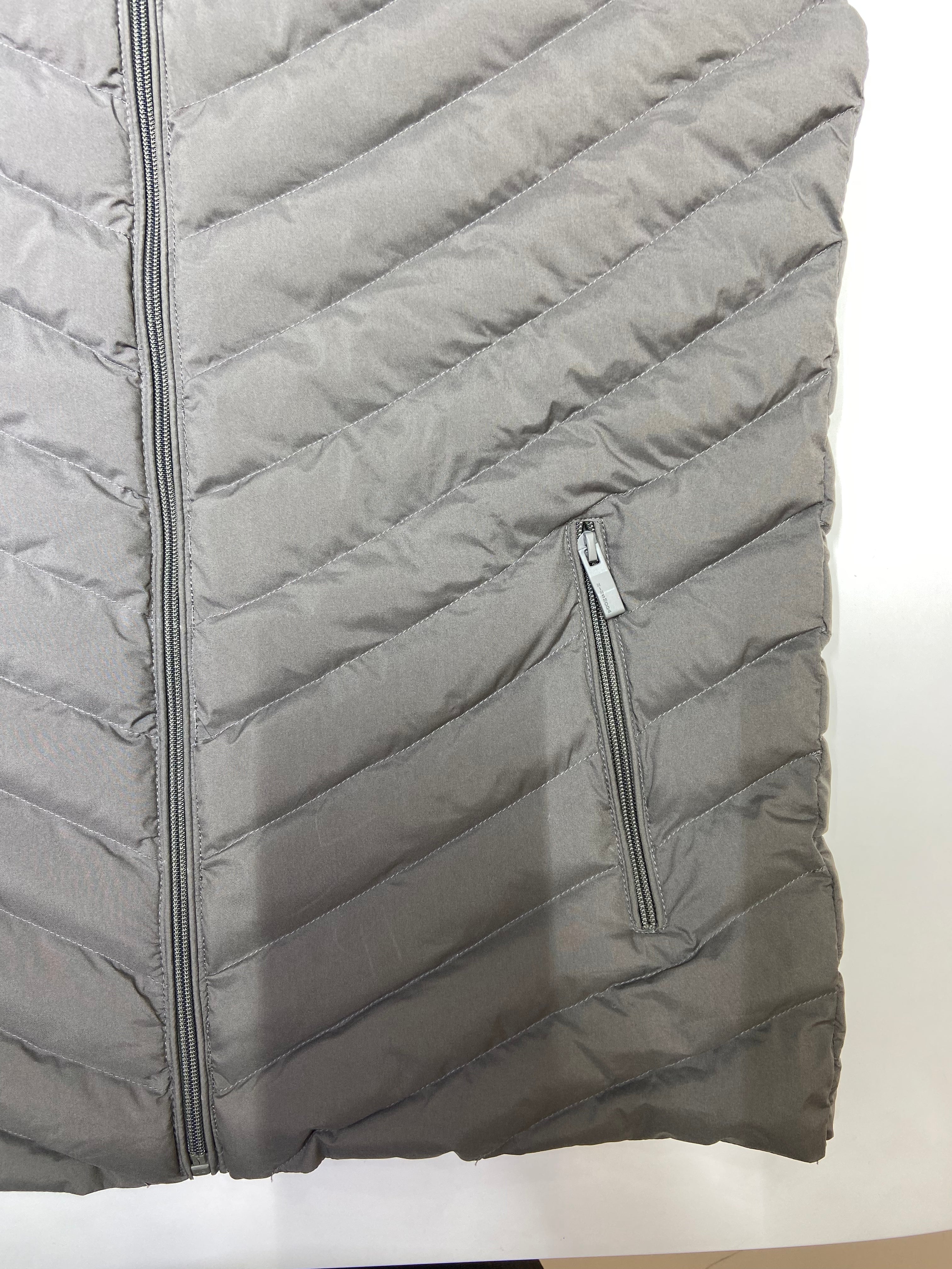Gray quilted jacket with a close detail of fabric, stitching and zippers on a white background